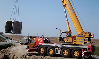 grue soulevant un pont cadre en béton